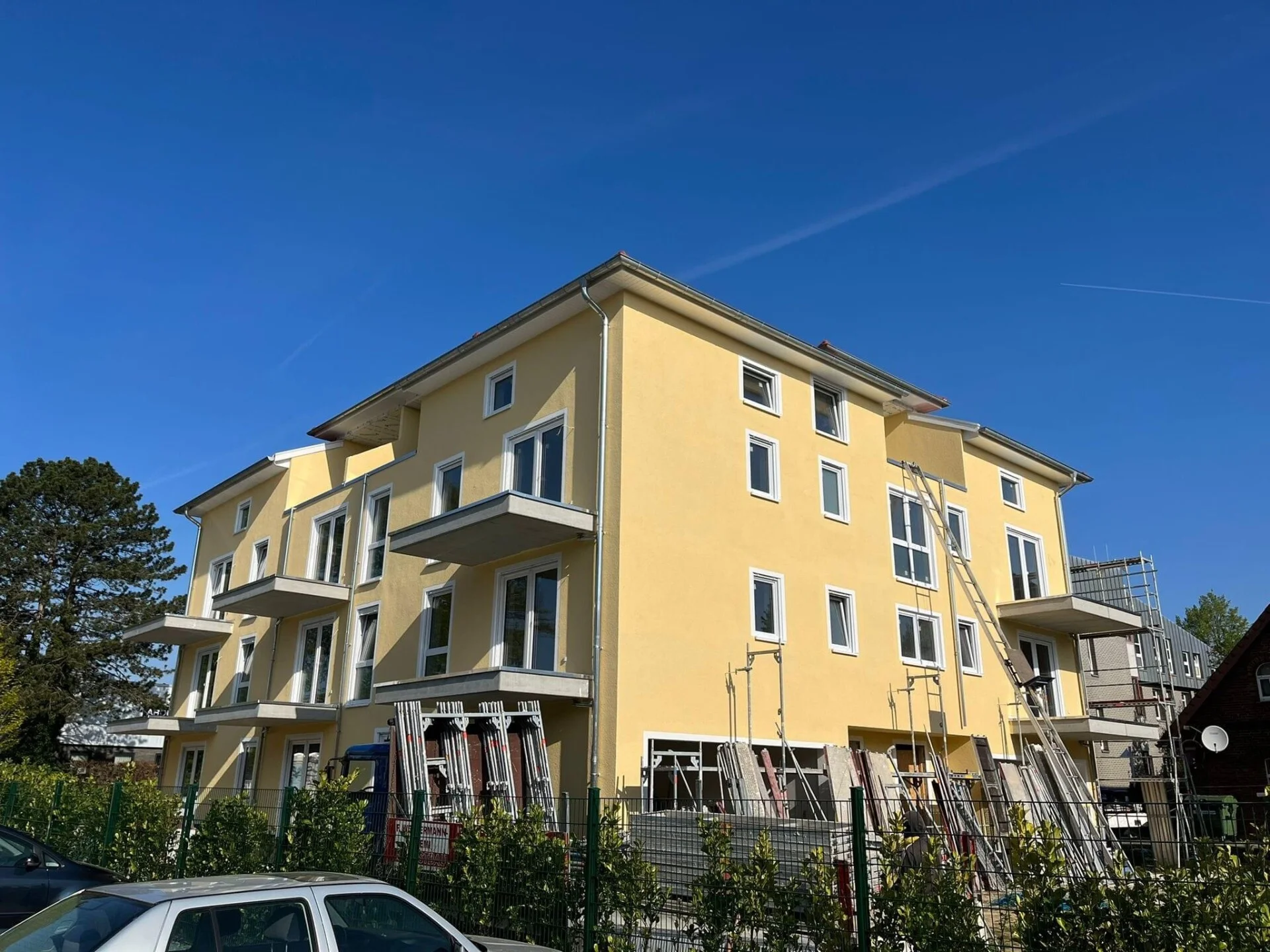 Neubau mit frisch gedämmter Fassade und Baukran im Hintergrund